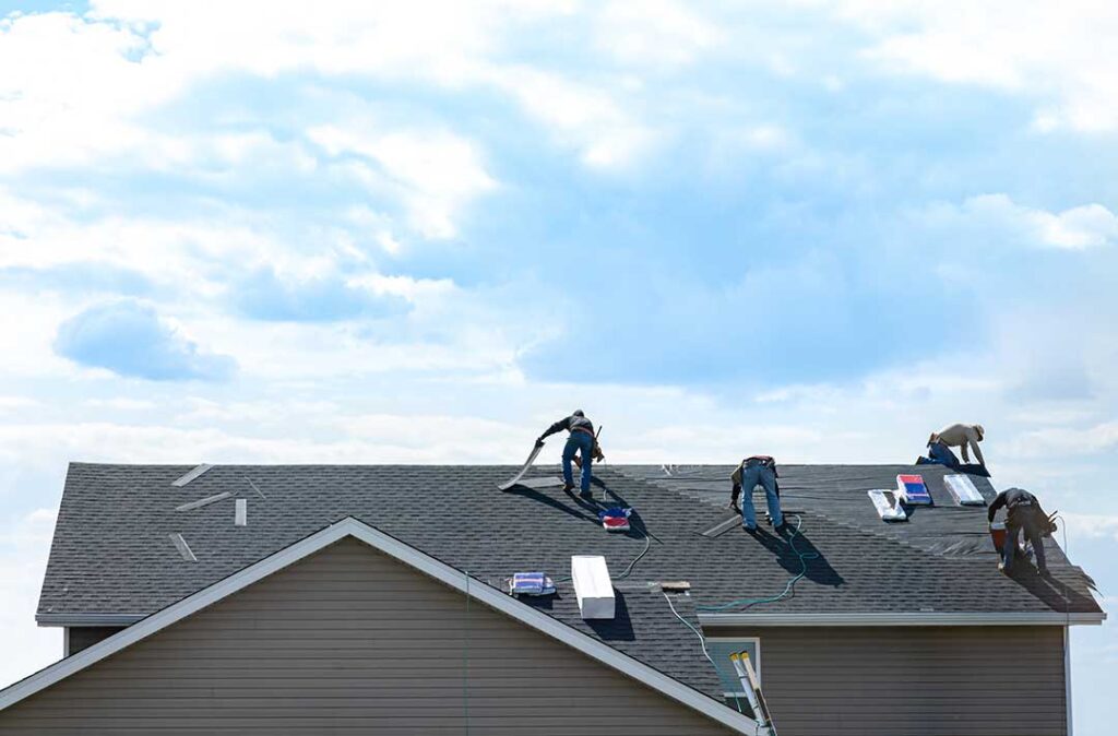 Homeowner reviewing roof warranty papers beside a folder of inspection records and roof photographs.