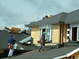A roofing inspector examining shingles with a clipboard and ladder visible against a residential roof.